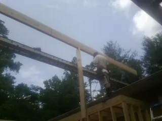 Carpenter setting a ridge beam over a new addition frame — Ice Dam Removal by Roofing Brothers in New England