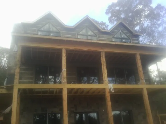 Dormers and porch framing on a large log home under construction — Roof Coating work by our crew in New England