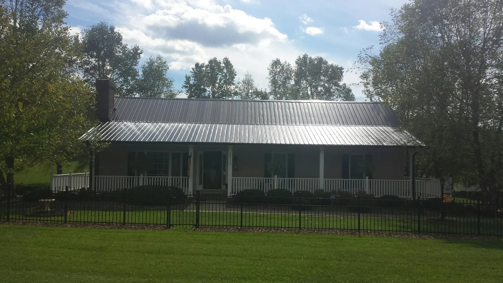 Gray metal roof on a brick ranch with a full width front porch — Gutter Guard Installation work by our crew in New England