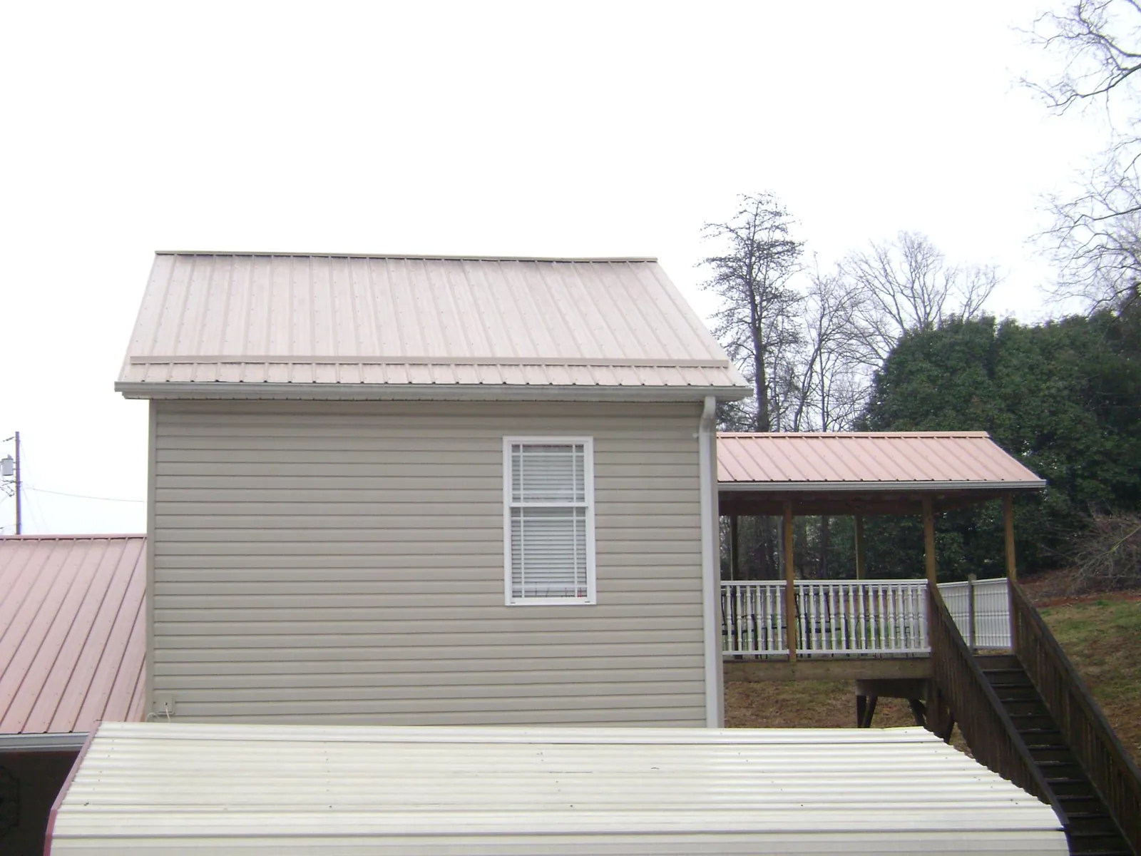 Tan metal roofs on a two story addition and attached porch, from a Roof Replacement job in New England