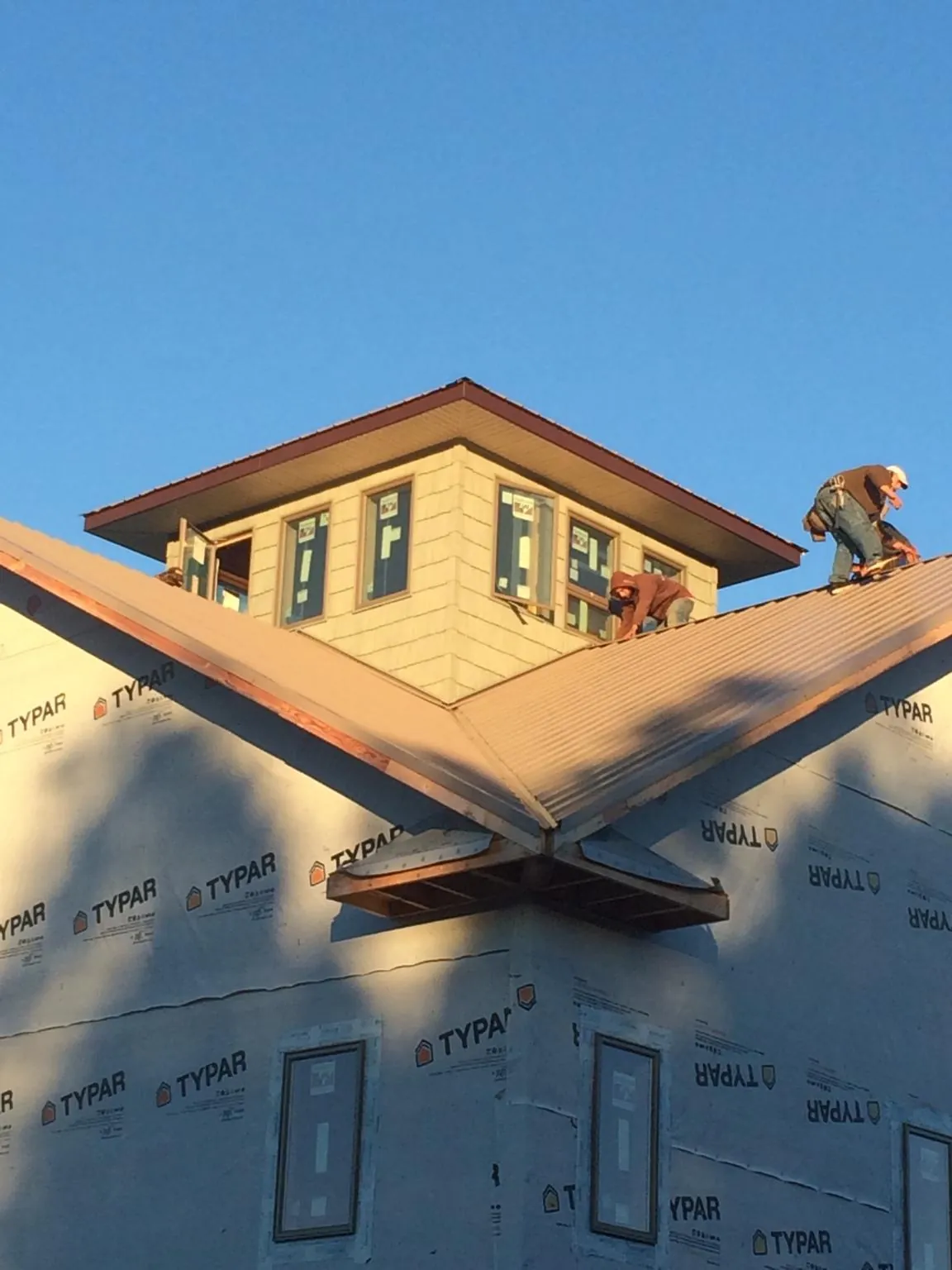 Roofers working around a rooftop cupola on a new metal roof at sunset — Roof Waterproofing in New England by Roofing Brothers
